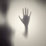 Una sombra negra con una mano empañada en una ventana de color negra y blanca.