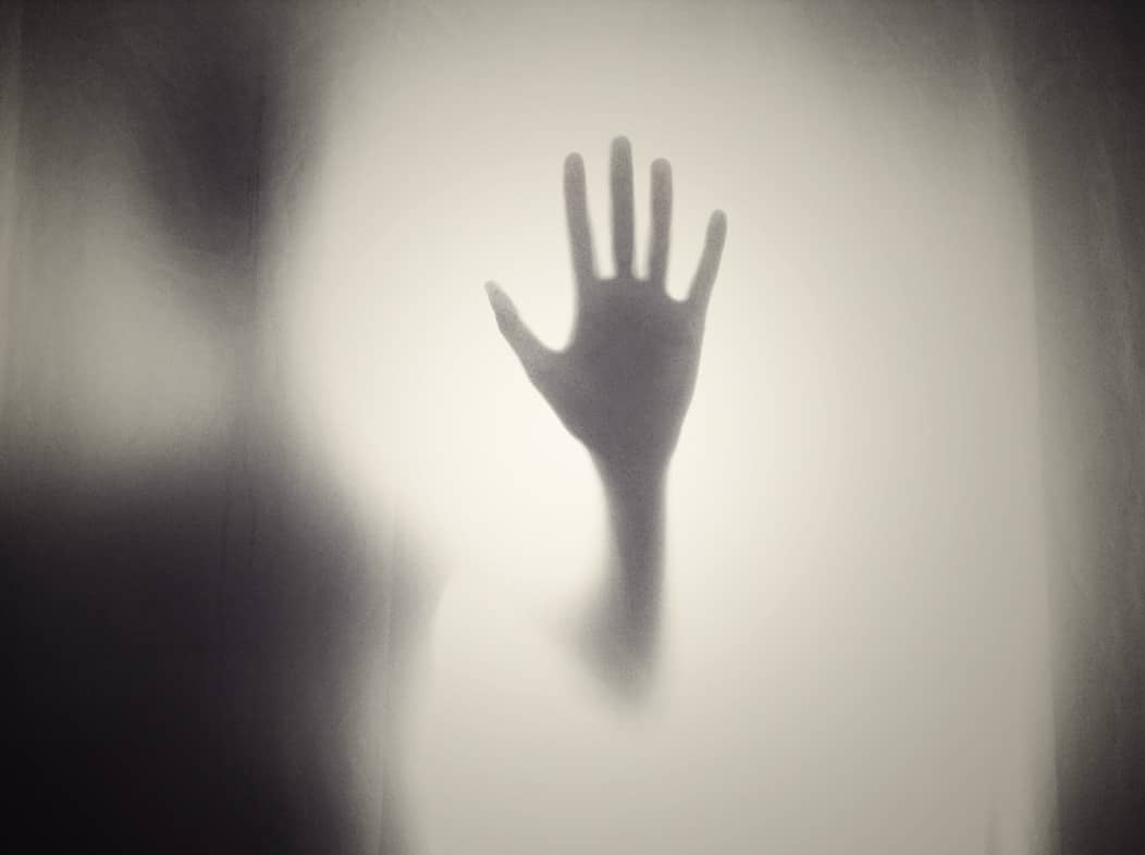 Una sombra negra con una mano empañada en una ventana de color negra y blanca.