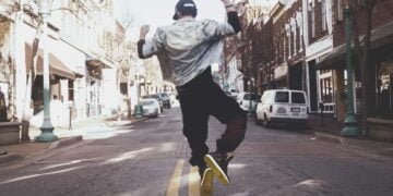 Un hombre saltando sobre una calle y esta de espalda.