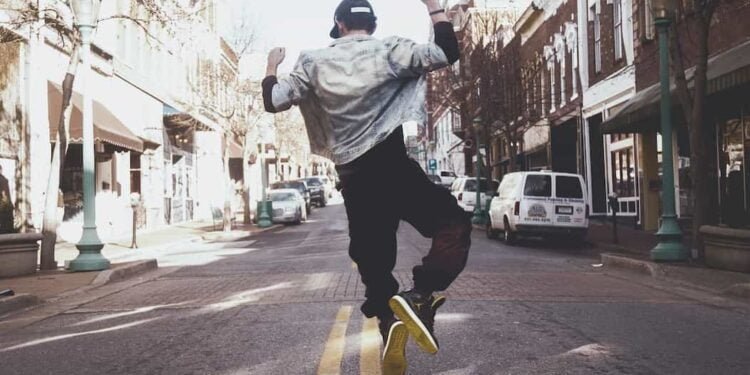 Un hombre saltando sobre una calle y esta de espalda.