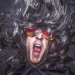 Hombre creativo gritando con un cabello gris y gafas.