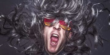 Hombre creativo gritando con un cabello gris y gafas.