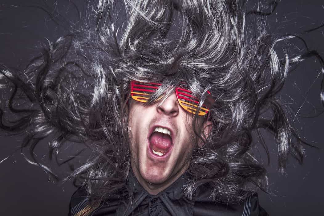 Hombre creativo gritando con un cabello gris y gafas.