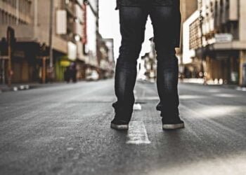 Una persona esta de espaldas en la calle, mostrando solamente sus pies en el Bronx.