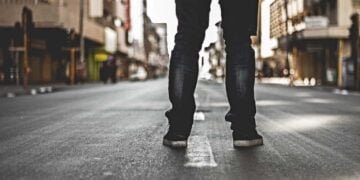 Una persona esta de espaldas en la calle, mostrando solamente sus pies en el Bronx.