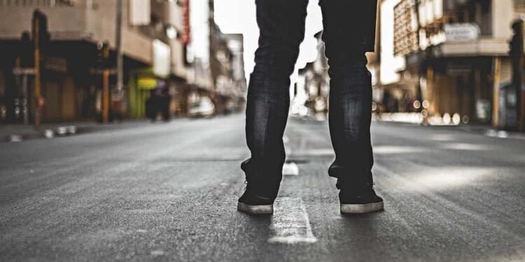 Una persona esta de espaldas en la calle, mostrando solamente sus pies en el Bronx.