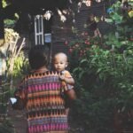 Una mujer con su hijo en brazos llegando a su casa.