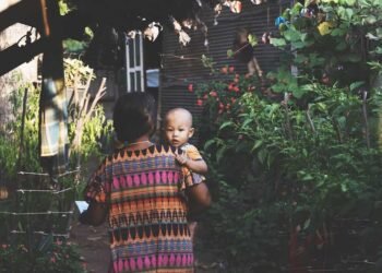 Una mujer con su hijo en brazos llegando a su casa.