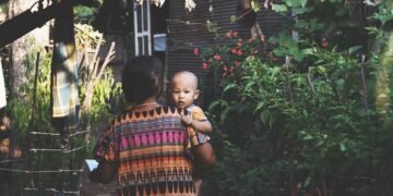 Una mujer con su hijo en brazos llegando a su casa.