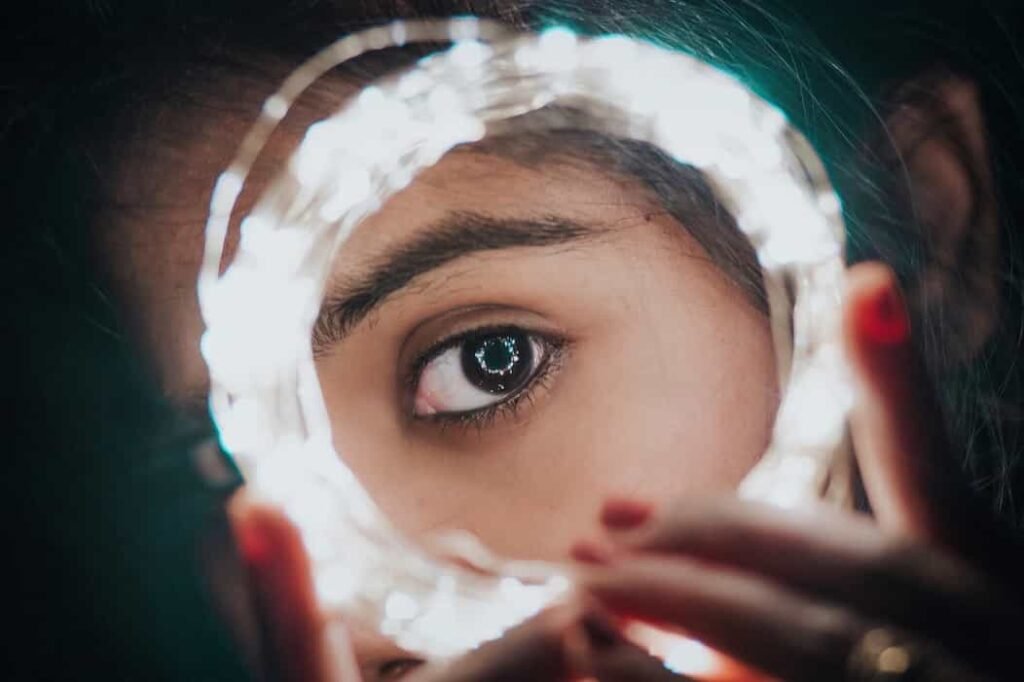 Una mujer mostrando su ojo en medio de unas luces en la noche del jardín botánico.