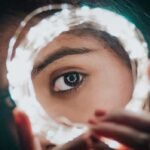 Una mujer mostrando su ojo en medio de unas luces en la noche del jardín botánico.