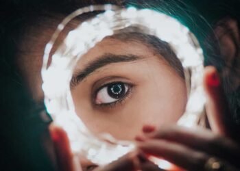 Una mujer mostrando su ojo en medio de unas luces en la noche del jardín botánico.