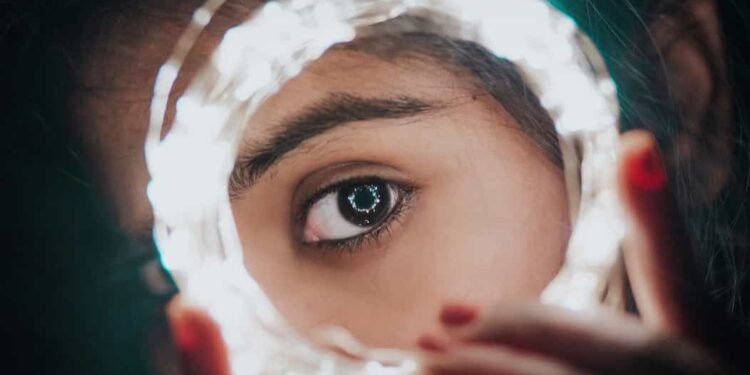 Una mujer mostrando su ojo en medio de unas luces en la noche del jardín botánico.