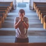 En la iglesia se encuentra un hombre resando, visitando las principales iglesias en la ruta vive Cundinamarca religiosa.
