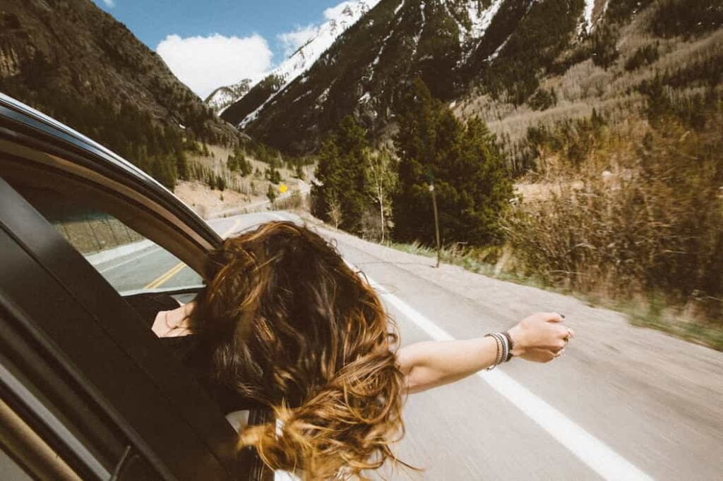 Mujer viajando por las carreteras de Cundinamarca celebrando la semana santa en su carro sacando la cabeza.