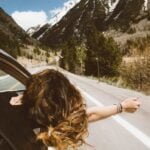 Mujer viajando por las carreteras de Cundinamarca celebrando la semana santa en su carro sacando la cabeza.
