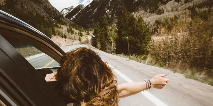 Mujer viajando por las carreteras de Cundinamarca celebrando la semana santa en su carro sacando la cabeza.
