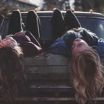 Dos mujeres acostadas en un carro sonriendo con aguardiente néctar