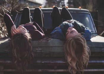 Dos mujeres acostadas en un carro sonriendo con aguardiente néctar