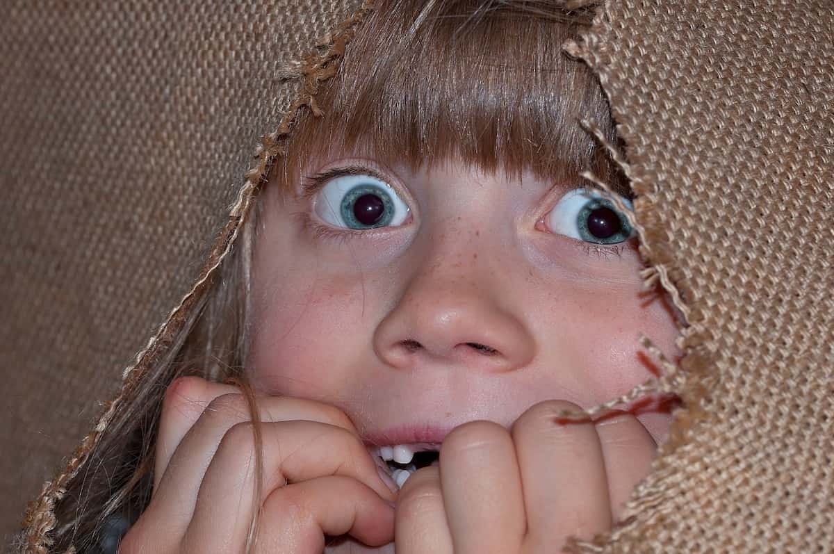 Una niña escondida y asombrada en medio de una tela.