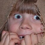 Una niña escondida y asombrada en medio de una tela.