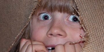 Una niña escondida y asombrada en medio de una tela.