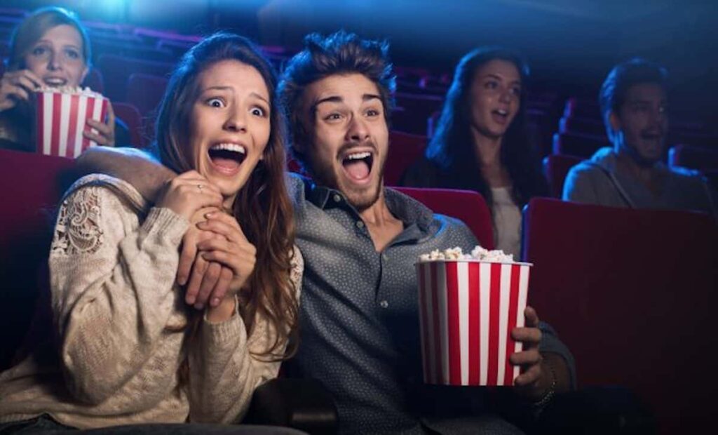 Una pareja esta en el cine sorprendida viendo el Guason y comiendo palomitas de maís.