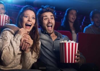 Una pareja esta en el cine sorprendida viendo el Guason y comiendo palomitas de maís.