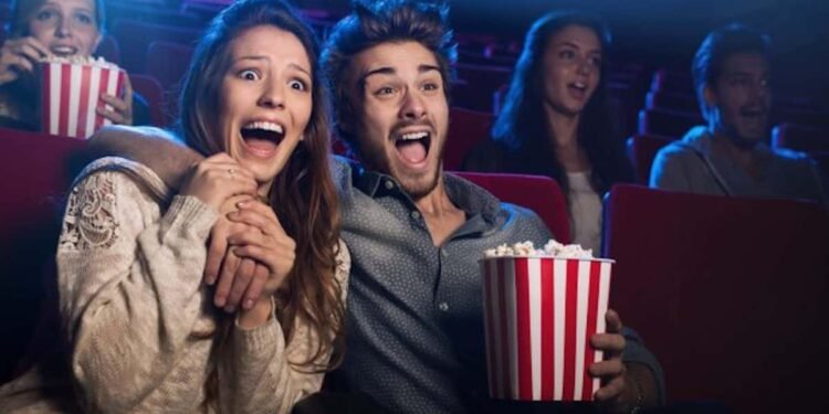 Una pareja esta en el cine sorprendida viendo el Guason y comiendo palomitas de maís.