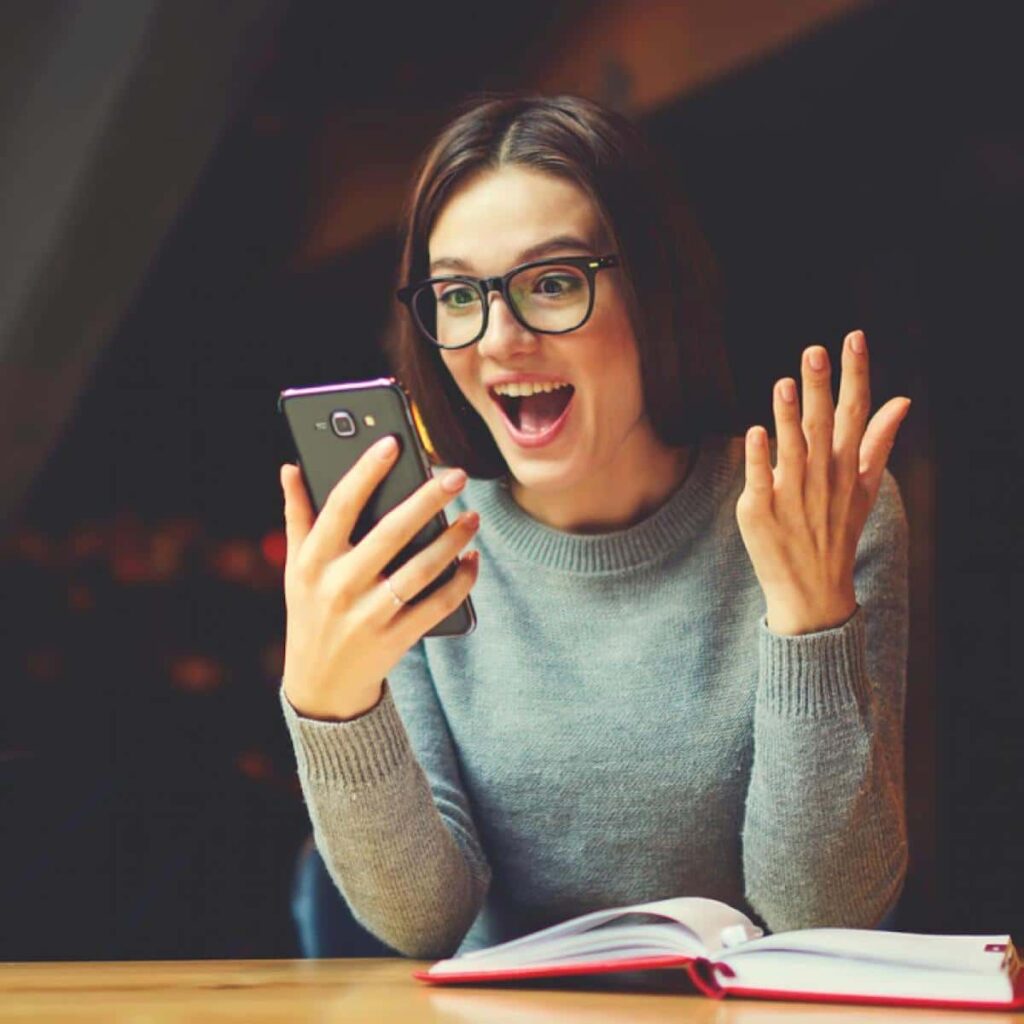 Una mujer en su escritorio mirando su celular sorprendida ¿Redes sociales en Política arma de doble filo para votar?