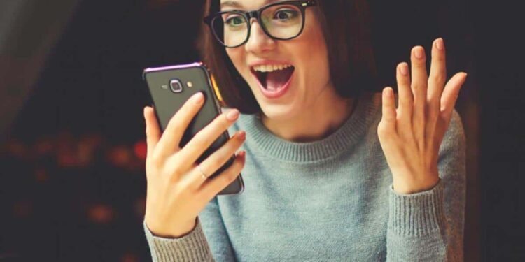 Una mujer en su escritorio mirando su celular sorprendida ¿Redes sociales en Política arma de doble filo para votar?