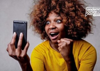 Una mujer mirando su celular sonriendo de alegría