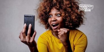 Una mujer mirando su celular sonriendo de alegría
