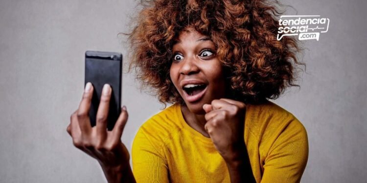 Una mujer mirando su celular sonriendo de alegría