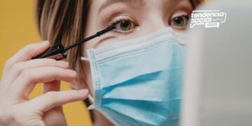 Mujer se esta mirando al espejo, usando el tapabocas.