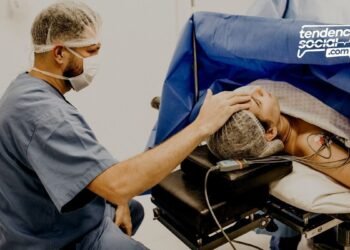 Un médico esta sentado atendiendo a un paciente acostado y tocándole la cabeza