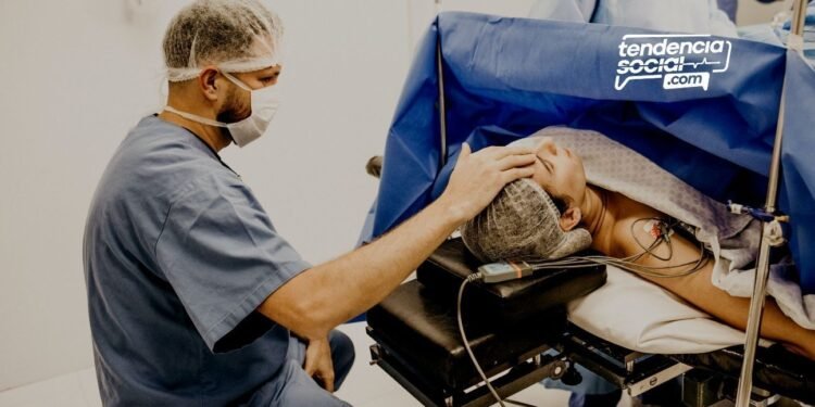 Un médico esta sentado atendiendo a un paciente acostado y tocándole la cabeza