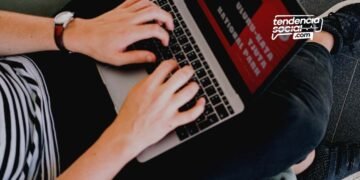 Persona sentada escribiendo en un computador.