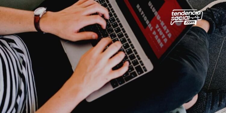 Persona sentada escribiendo en un computador.