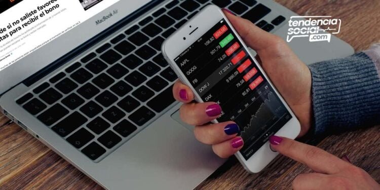 Una persona con su celular y su computador mirando la lista de bonos.