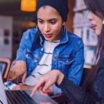 Dos mujeres están viendo el computador en un escritorio
