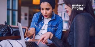 Dos mujeres están viendo el computador en un escritorio