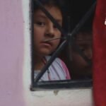 Una persona alzando la mano y agarrando en una ventana un trapo rojo