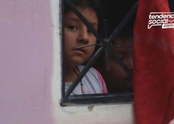 Una persona alzando la mano y agarrando en una ventana un trapo rojo
