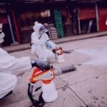 Dos personas están fumigando las calles de los negocios que cierran en corabastos