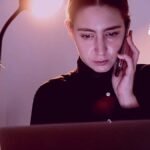 Una mujer en su casa con su telefono y celular