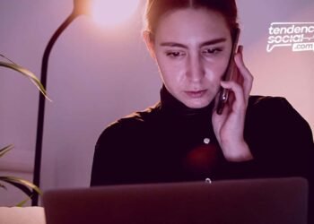 Una mujer en su casa con su telefono y celular