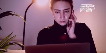 Una mujer en su casa con su telefono y celular