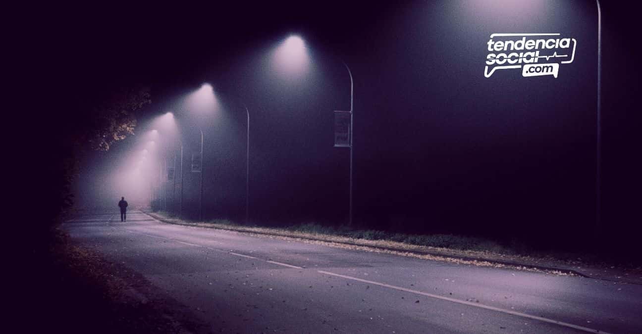 Una calle en la oscuridad y una persona a lo lejos.