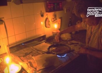 Una mujer en la cocina sin luz con una vela corte de luz en soacha por mantenimiento